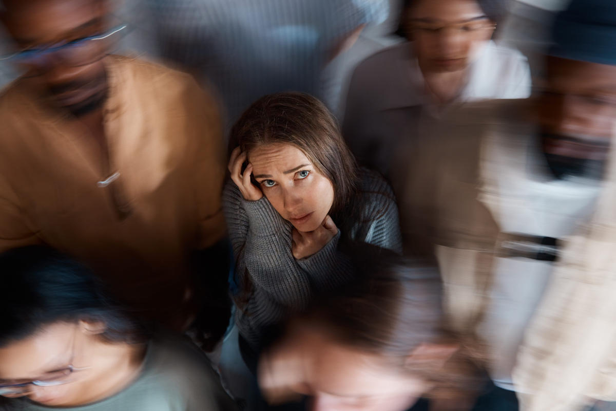 Young woman alone in a room full of people