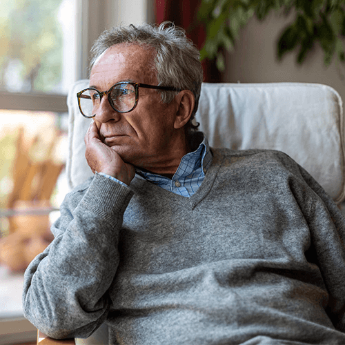 Older man patient of Balanced Mental Health of Arizona looking off to the side while sitting down.