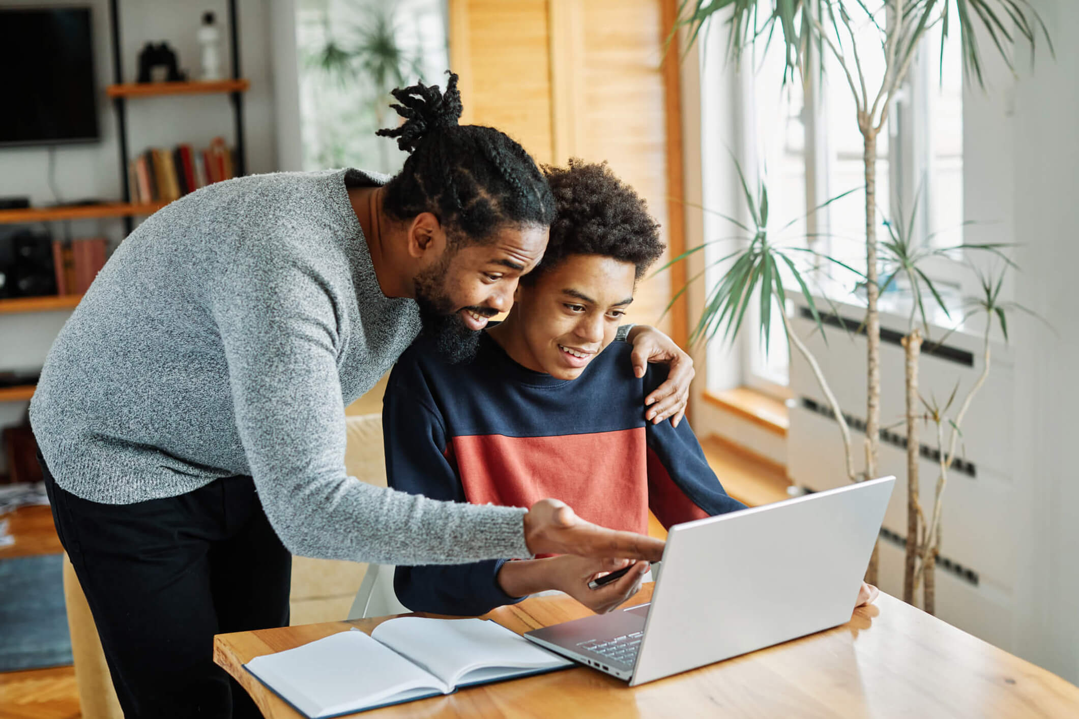 Father and son sitting at a laptop at a kitchen table filling out ADHD screening forms for Balanced Mental Health of Arizona.