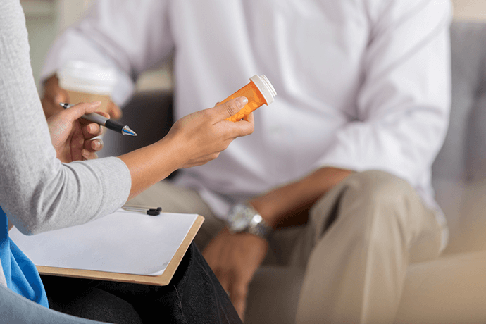 Hand of a mental health professional at Balanced Mental Health of Arizona holding a prescription pill bottle while talking to patient.