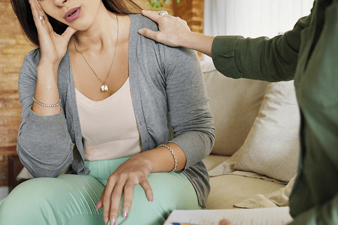 Young woman in distress being consoled.