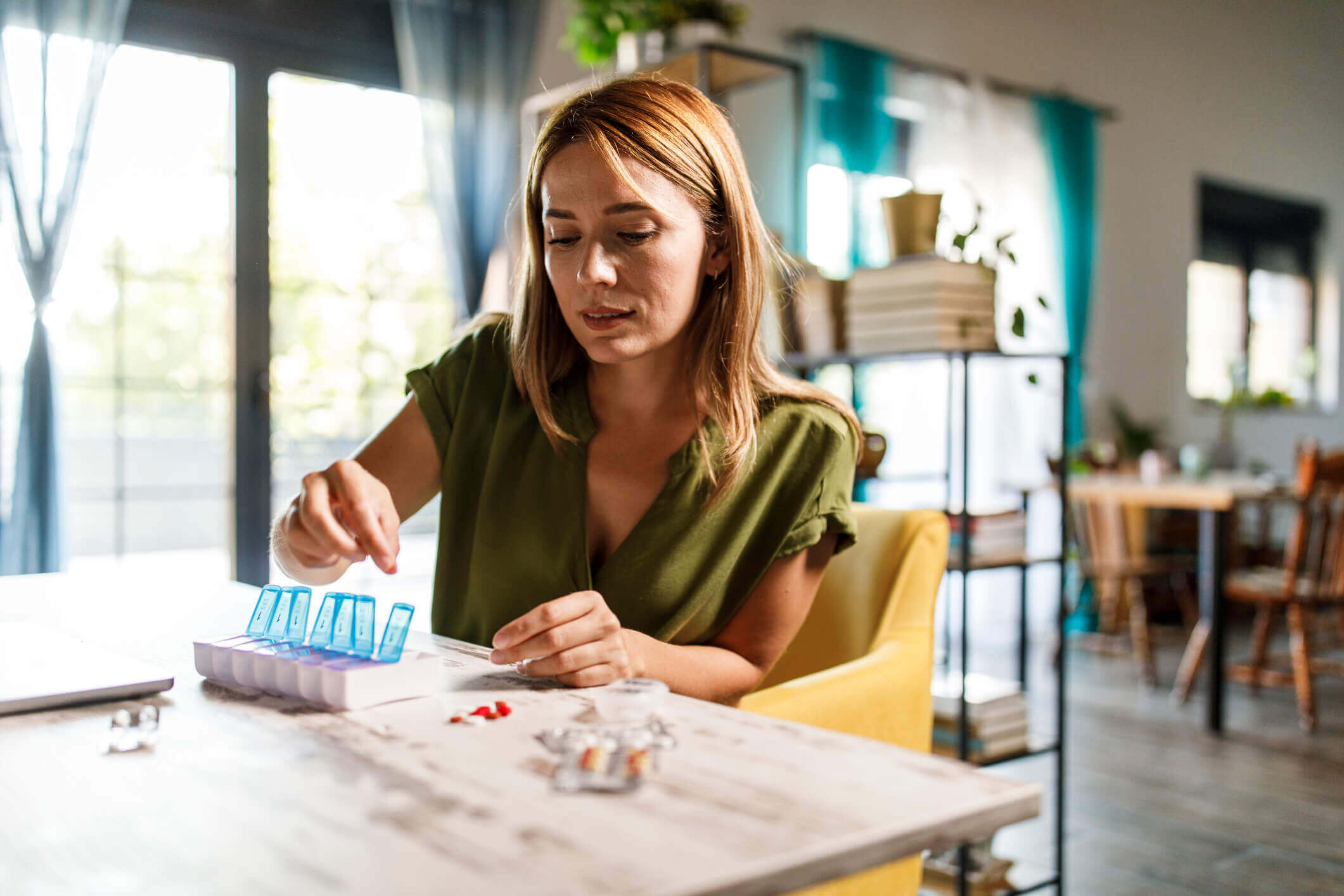 Young woman sitting at a table organizing her medication following her consultation at Balanced Mental Health of Arizona.