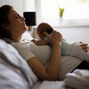 Young mother and patient of Balanced Mental Health of Arizona holding and trying to soothe an infant.